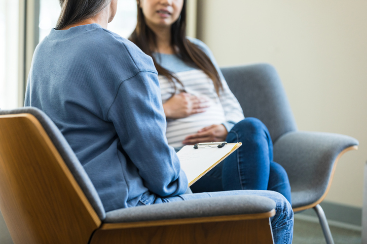 Photo shows a female healthcare worker and a pregnant woman having a serious conversation/Getty Images