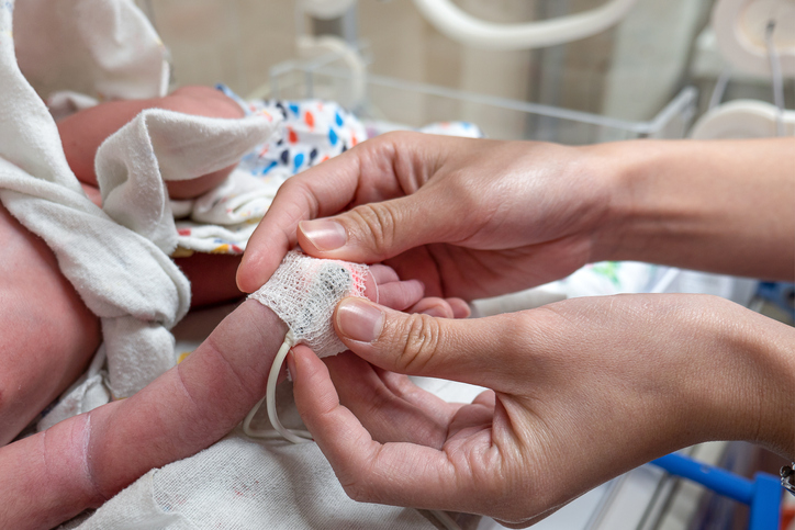 Photo shows a nurse applying an oximeter on a newborn infant.