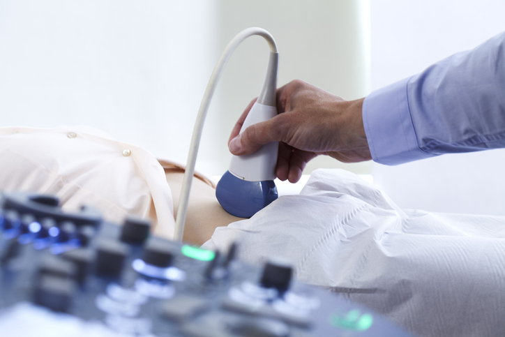 Photo shows doctor performing a pregnancy ultrasound scan.