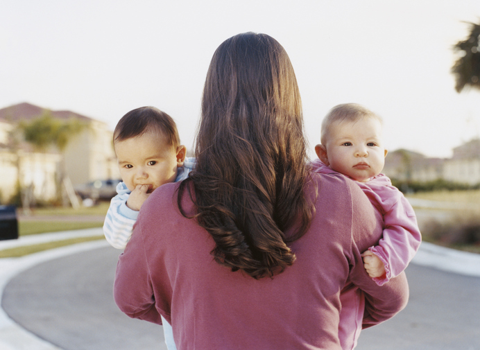 Photo shows a woman holding twin babies