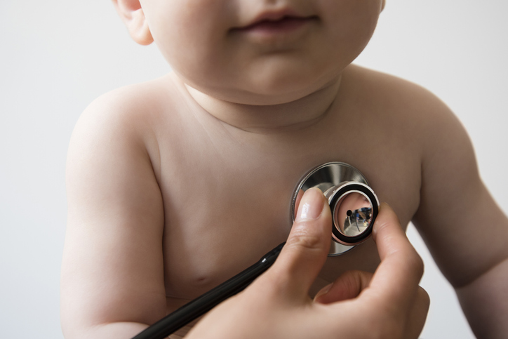 Photo shows doctor listening to chest of baby boy with stethoscope