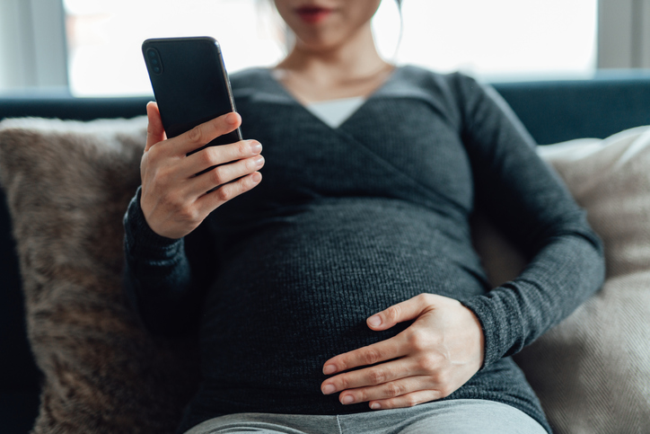 Photo shows pregnant woman using smartphone