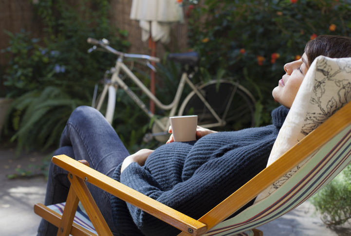 Photo shows pregnant woman relaxing on deck chair with a cup of tea
