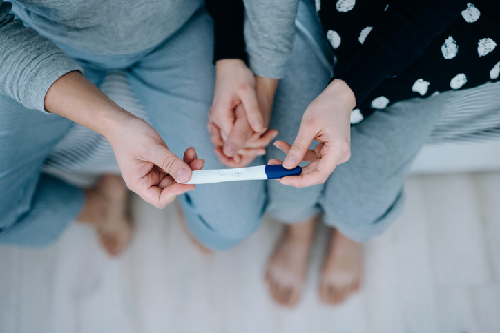 Photo shows a couple holding a positive pregnancy test