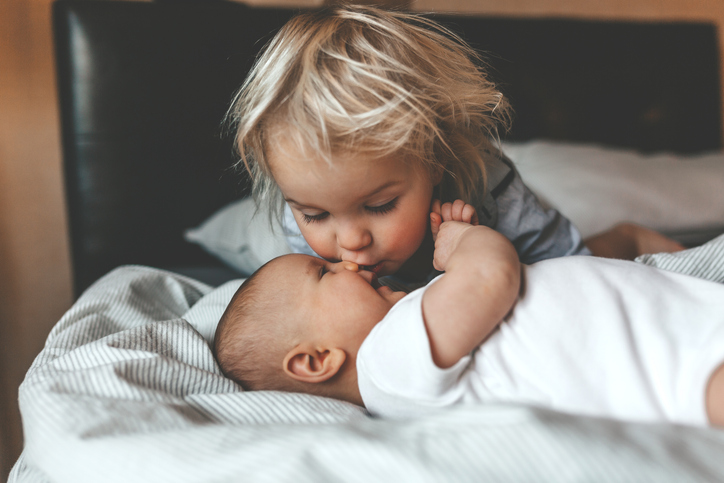 Photo shows a brother hugging his newborn sister/Getty Images