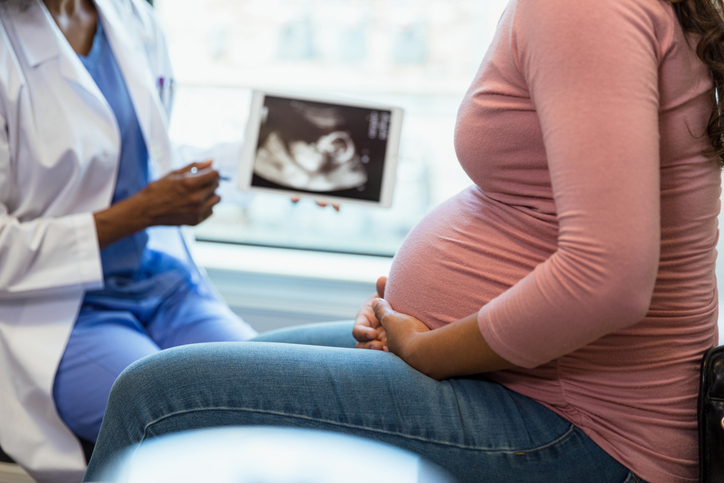 Photo shows a doctor and pregnant patient discussing an ultrasound/Getty Images