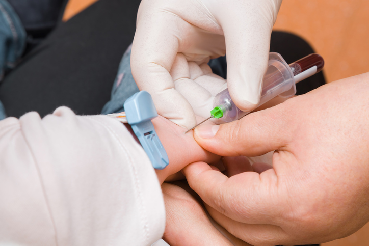 Photo shows doctor drawing blood from an infant's hand/Getty Images