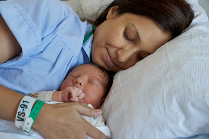 Photo shows a mother lying on a couch with her newborn baby/Getty Images