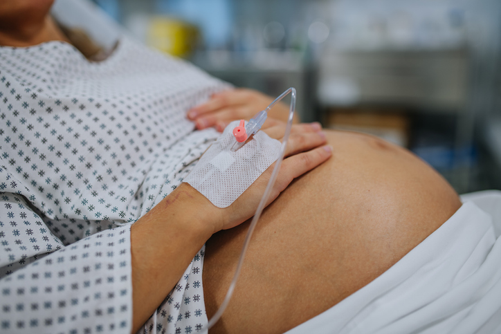 Photo shows a woman in labor holding her belly in a hospital bed/Getty Images