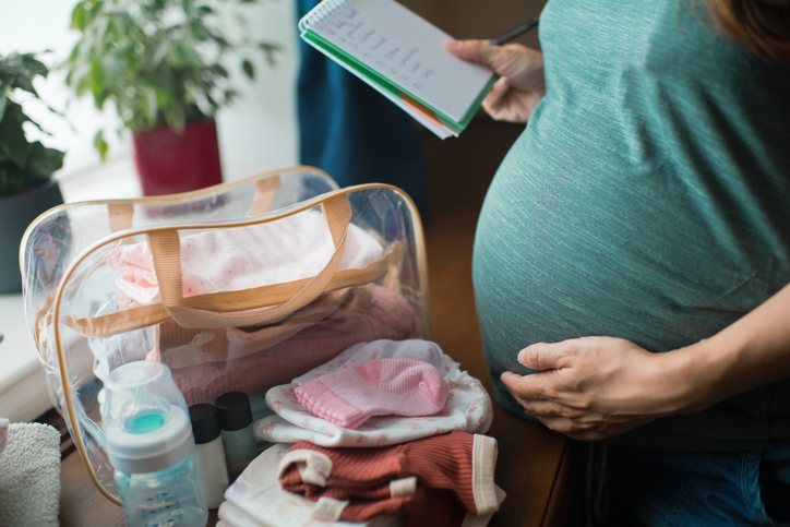 Photo shows a pregnant woman at home preparing bag for newborn baby/Getty Images