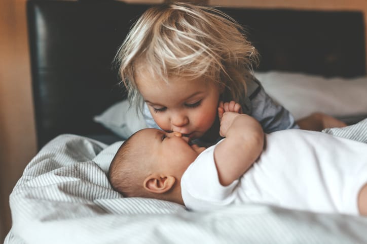 Photo shows a toddler kissing his newborn sibling/Getty Images