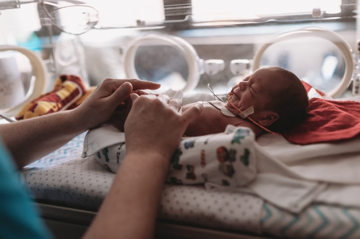 Photo shows a NICU baby being assisted by mother while he is in his incubator/Getty Images