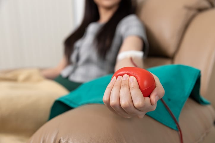 Photo shows a woman squeezing a ball while she donating blood/Getty Images