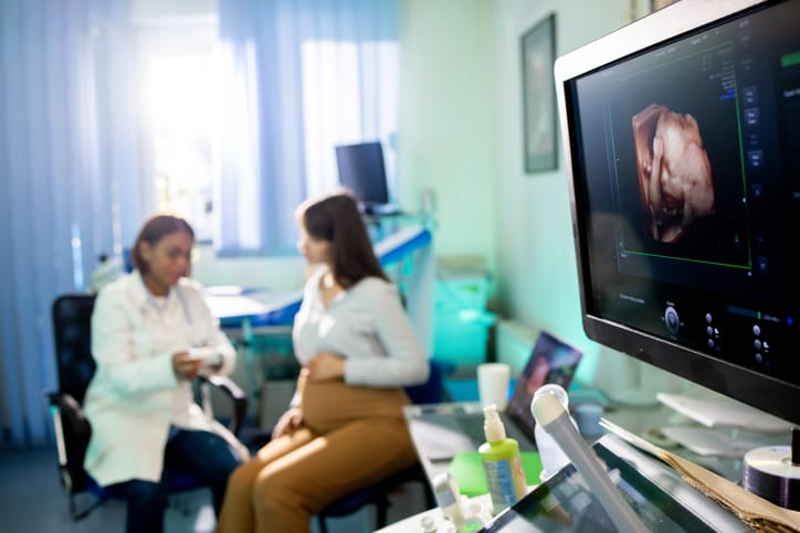 Photo shows a young pregnant woman having a medical consultation with a female gynecologist/Getty Images