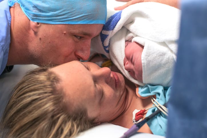 Photo shows a husband and wife holding their newborn baby for the first time after a C-section/Getty Images
