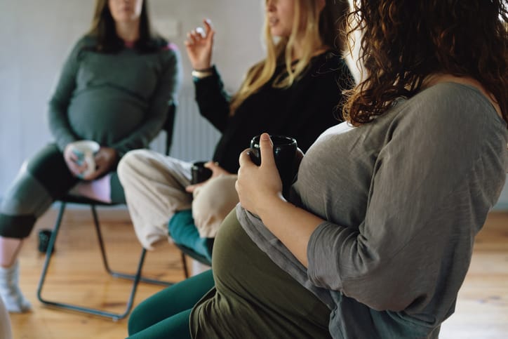 Photo shows three pregnant women sitting in chairs at a prenatal workshop/Getty Images
