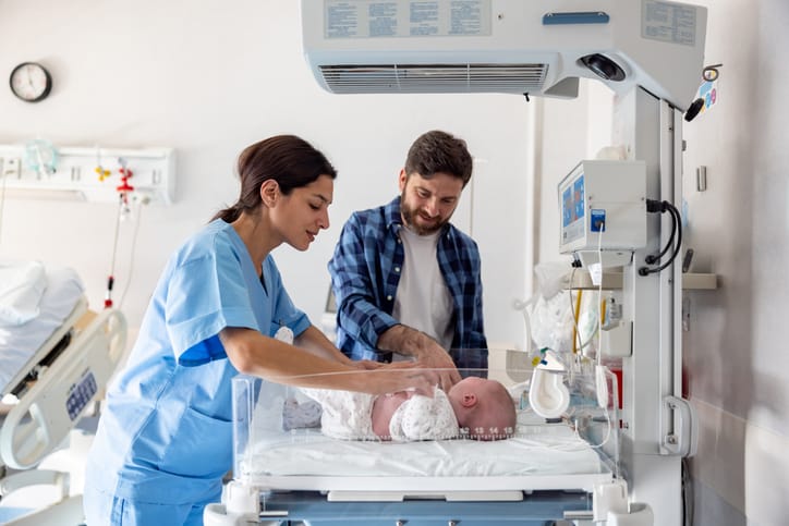Photo shows a midwife introducing a happy father to his newborn baby who is lying in an incubator/Getty Images