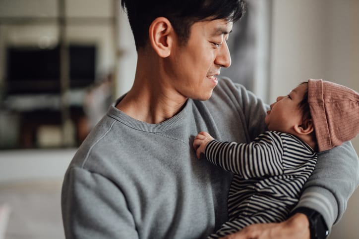 Photo shows a father holding and smiling at his baby/Getty Images