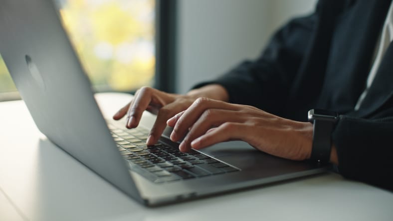 Photo shows a close-up hand of man typing on a laptop/Getty Images