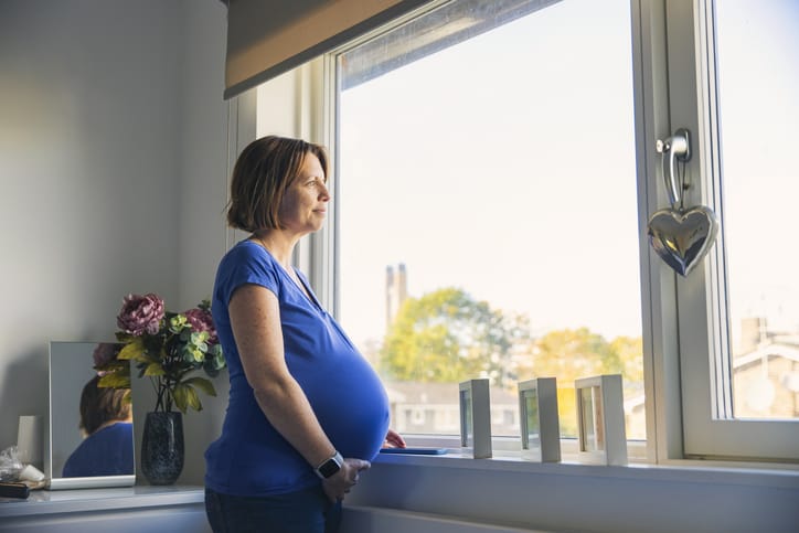 Photo shows a pregnant woman looking out of her window/Getty Images