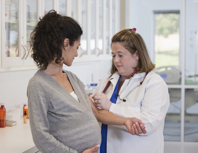 Photo shows a pregnant woman having her blood drawn at a doctor's office/Getty Images