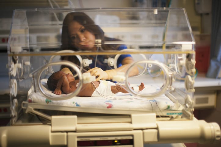 Photo shows a nurse checking on a newborn in an incubator/Getty Images
